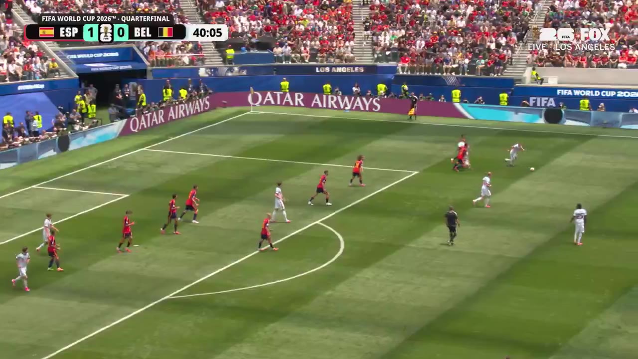 Soccer match between Spain and Belgium at what appears to be a World Cup quarterfinal; scoreboard shows the score changing from 1-0 to 1-1, with players in red/dark kits (Spain) and white kits (Belgium) contesting play near the goal area, followed by a close-up of a Belgium player in a white kit celebrating.