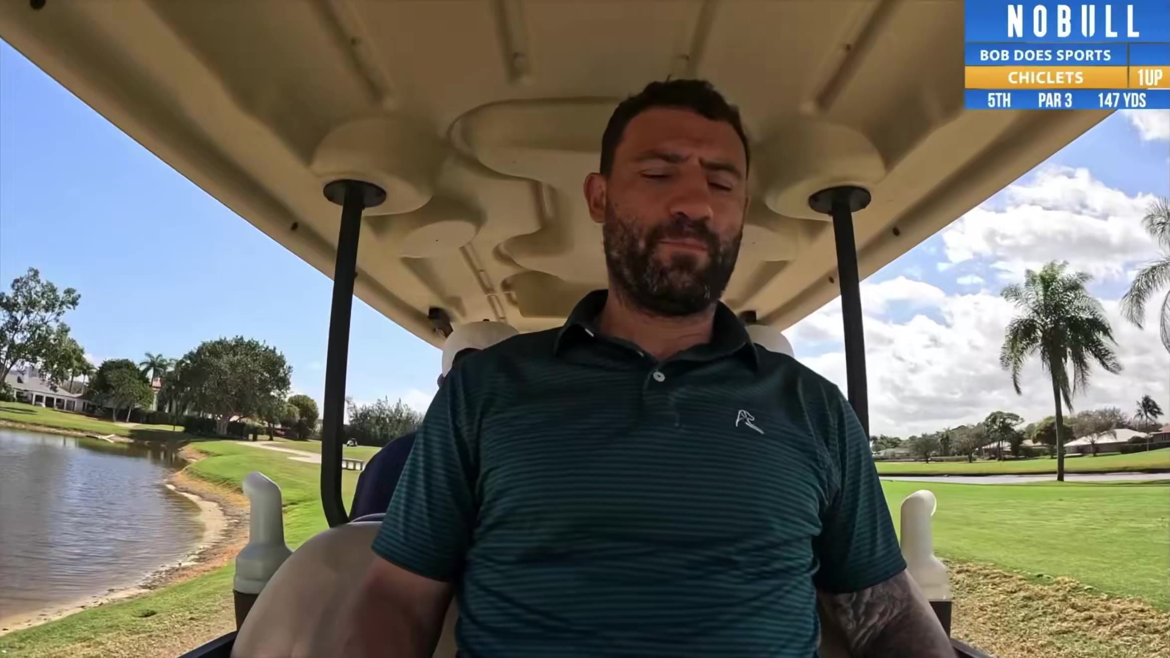 A golfer in a teal polo walks off the tee with a golf club and glove in hand, then a golf ball is shown resting on the fairway near a divot, with a scoreboard graphic showing hole 5, par 3, 147 yards, and a cameraman and another man filming nearby.