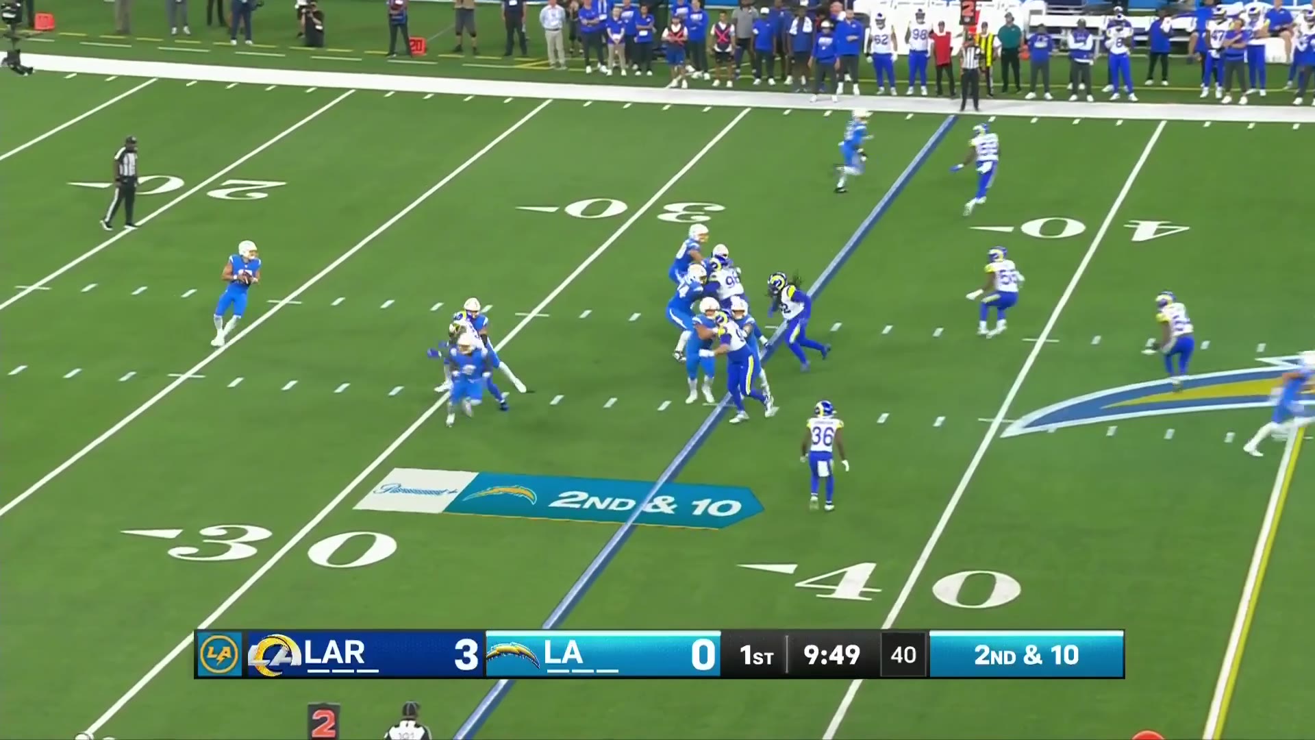 NFL game footage of the Los Angeles Chargers hosting the Los Angeles Rams, with the scoreboard reading LAR 3, LA 0, 1st quarter, 9:46-9:41, 2nd and 10 at the 40; a Chargers receiver runs a route downfield near midfield while defended by a Rams defensive back, then Chargers quarterback #10 is shown on the field afterward.
