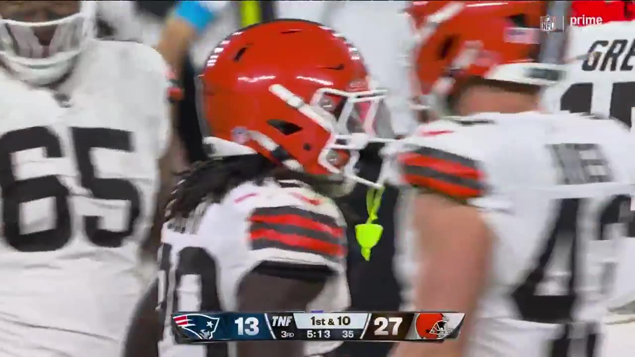 Cleveland Browns offense running a play against the New England Patriots, with a running back carrying the ball before being tackled by Patriots defenders; scoreboard shows Patriots 13, Browns 27, 3rd quarter 4:49, 1st and 10.