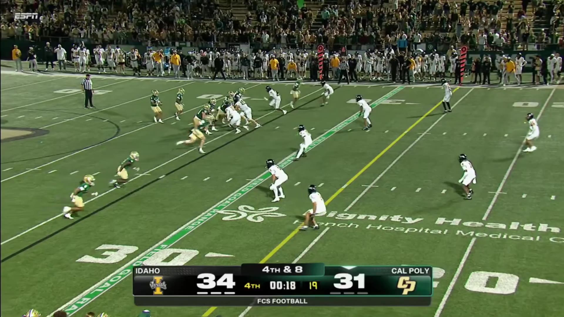 Cal Poly's white-jerseyed offense scores a touchdown in the end zone late in the 4th quarter against Idaho, with the scoreboard reading Idaho 34, Cal Poly 37 and 0:09 left, sparking a crowd celebration.