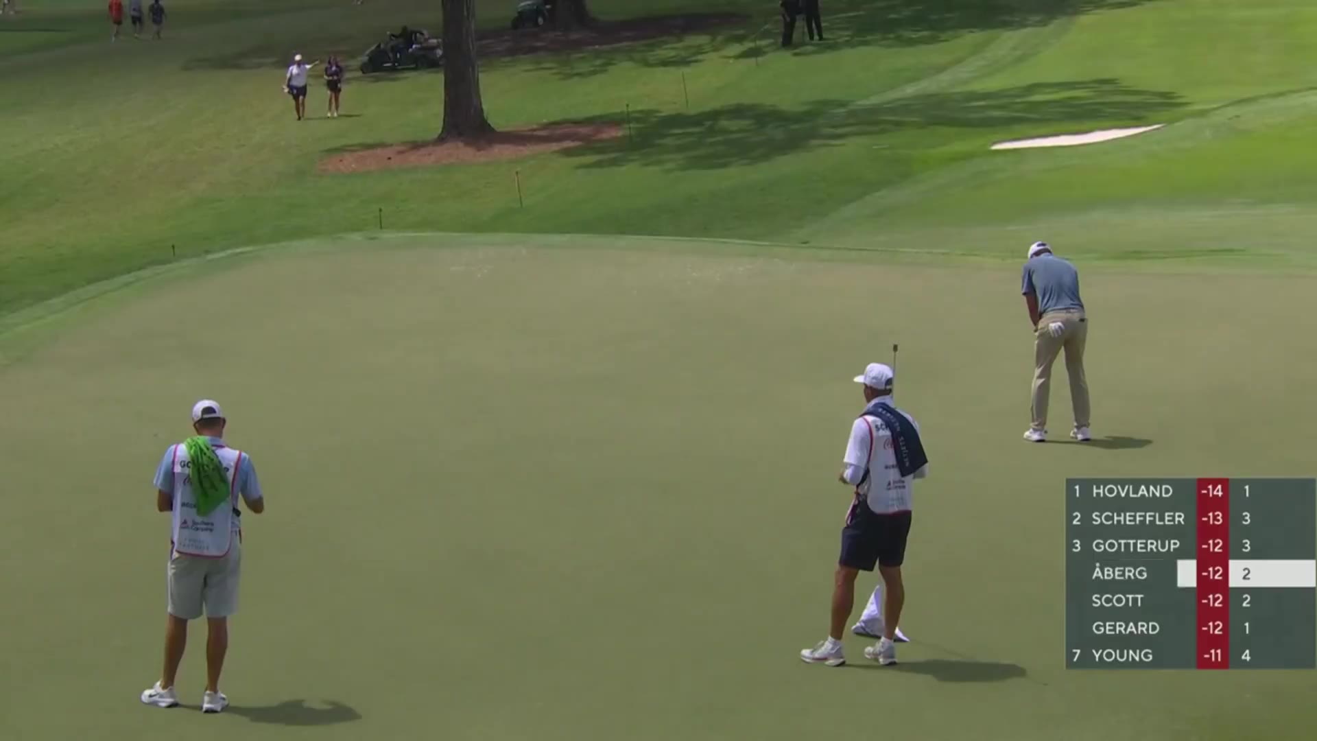 Scottie Scheffler, wearing a white cap and light blue Nike polo, walks the course and looks down at a leaderboard scorecard graphic showing him tied atop the standings, then stands near a hole-number sign with his golf bag beside a PGA Tour logo.