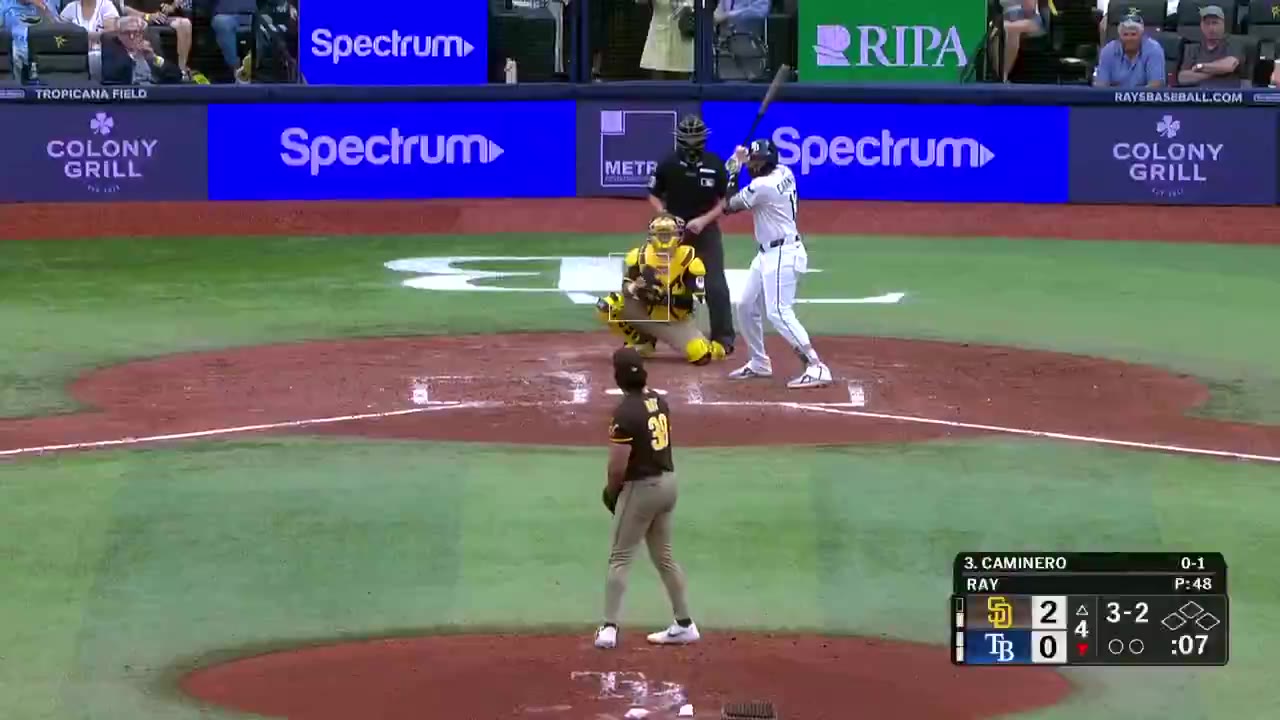 Tampa Bay Rays batter rounds the bases after a hit, with the on-screen line showing Rays trailing San Diego 0-2 in the 4th inning, then a stadium crowd shot, then a player jogging past the on-deck area