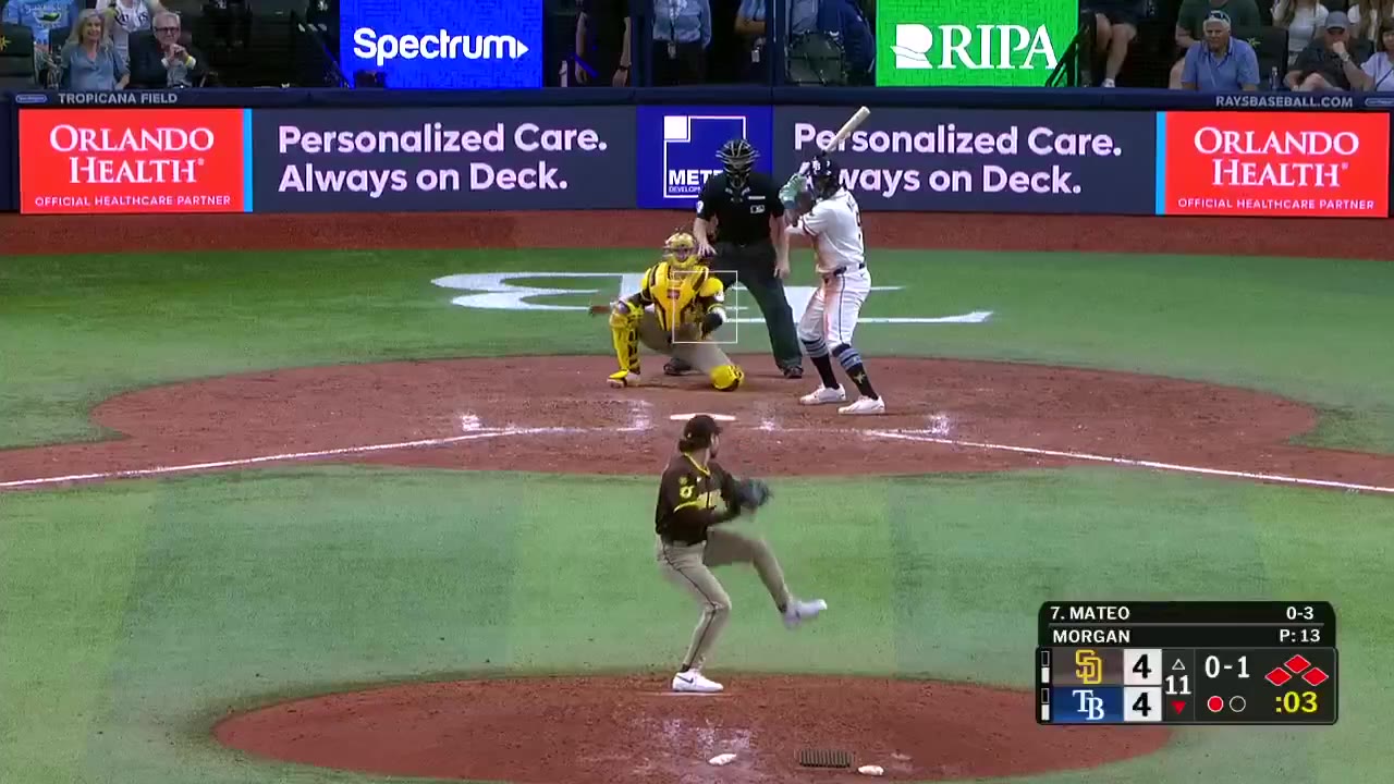 A San Diego Padres outfielder (No. 0) jogs on the field near the 378 marker with SD leading TB 4-4 in the 11th, then Tampa Bay Rays players including No. 6 Walls and No. 13 Camero mob teammates near home plate as the scoreboard shows Final/11 Padres 4, Rays 5.