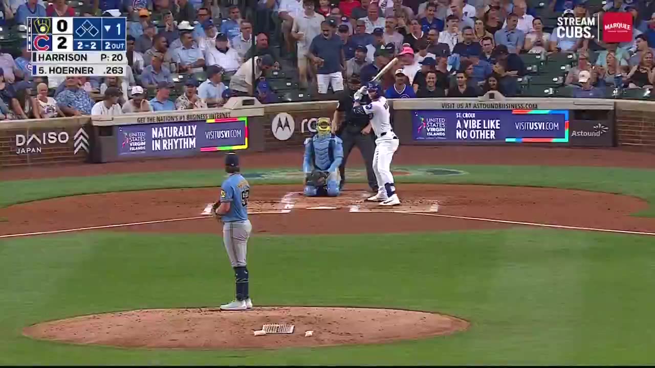 Nico Hoerner rounds the bases after hitting a home run against the Milwaukee Brewers, with an on-screen graphic reading '8th home run this season' and fans celebrating in the outfield stands at Wrigley Field.