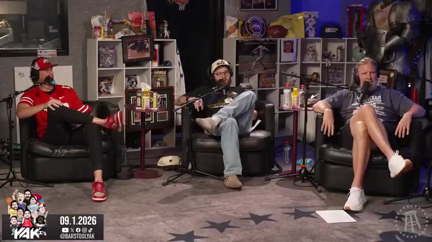 Two podcast hosts seated in studio chairs on a set with 'YAK' branding and caricature artwork, discussing content while a Google Maps satellite view showing the Iowa/Illinois border region and Chicago area is displayed on screen.