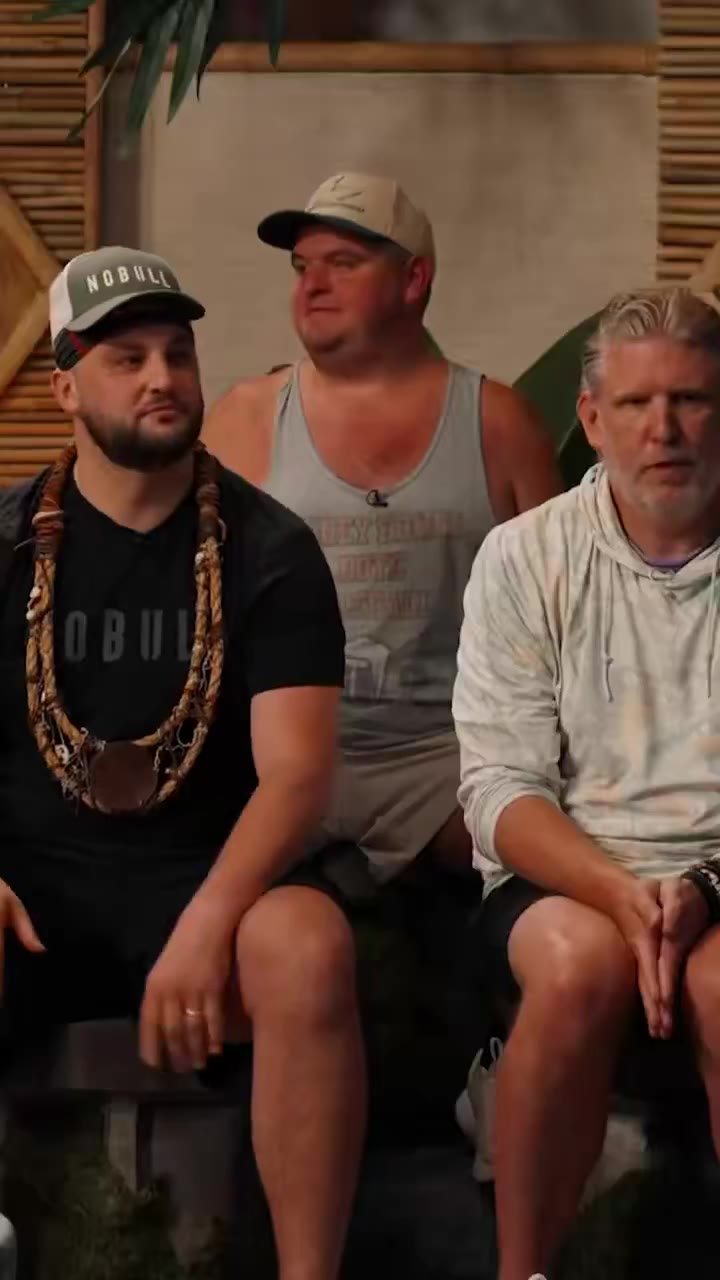 A group of men sit around a fire pit set; one man in a gray shirt clutches his head in shock while another in a white 'THE JOV' shirt sits beside him, followed by a bearded man in a NOBULL shirt speaking mid-sentence, then a man in a Barstool Sports camo hat shown against a dark studio backdrop.