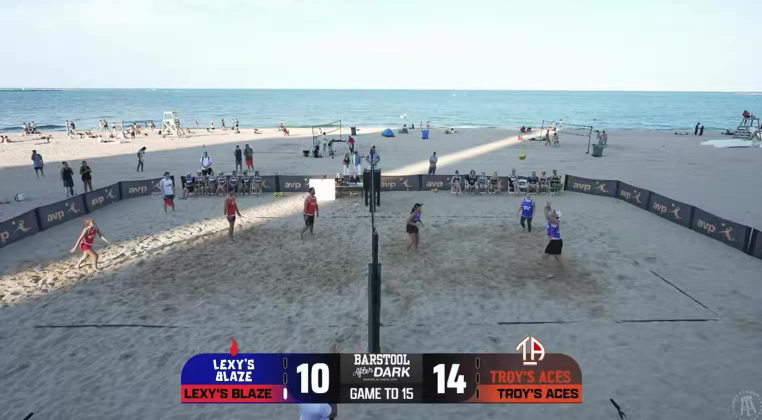 AVP beach volleyball match between Lexy's Blaze (red jerseys) and Troy's Aces (blue/orange jerseys), with a referee on a raised stand at the net gesturing during a dispute; scoreboard shows Lexy's Blaze 11, Troy's Aces 14, Game to 15, presented with a Barstool After Dark overlay.